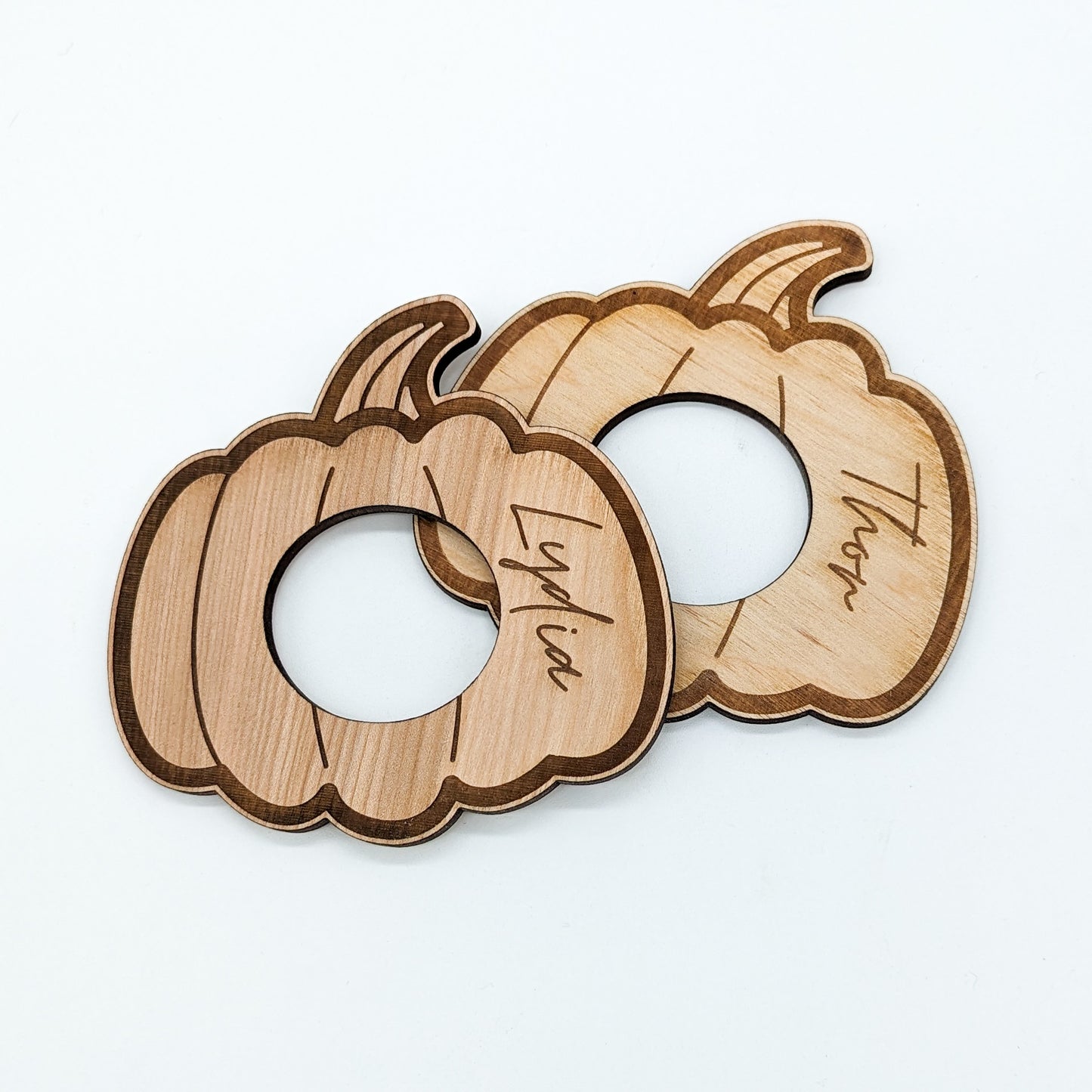 2 flat wooden pumpkin napkin rings engraved with names in a script font