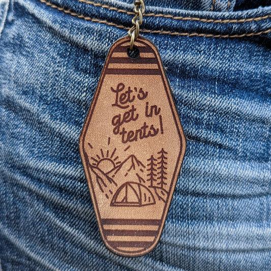 Leather Keychain cut with Lets get in tents tent in the mountains line illustration engraved on it.