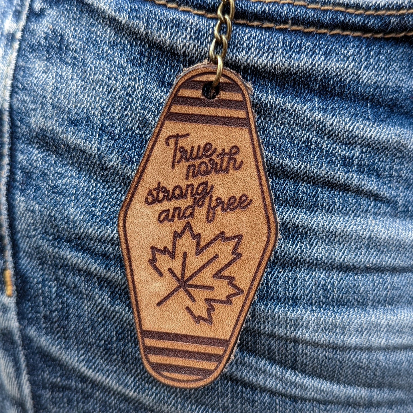 Leather Keychain cut and engraved to look like a vintage motel key with True North Strong and free and an illustration of a maple leaf engraved on it.