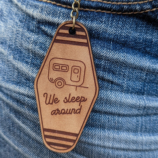 Leather Keychain cut and engraved to look like a vintage motel key with a line illustration of a camping trailer and We sleep around engraved on it.