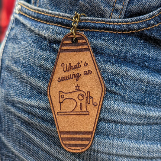 Leather Keychain cut and engraved to look like a vintage motel key whats sewing on and an line illustration of a sewing machine engraved on it.